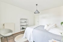 Інтер'єр сучасної спальні з м'яким ліжком і дерев'яним приліжковим столом, розробленим в мінімальному стилі в квартирі — стокове фото