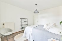 Interior of contemporary bedroom with soft bed and wooden bedside table designed in minimal style in flat — Stock Photo