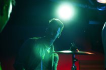 Gravi giovani ragazzi che eseguono musica alla batteria in club con luci verdi e blu al neon — Foto stock