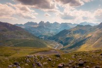 Valle verde con colline erbose situate contro montagne rocciose ruvide e cielo nuvoloso nella natura selvaggia della Spagna il giorno d'estate — Foto stock