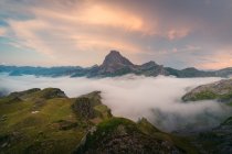 Névoa branca grossa flutuando perto do cume rochoso áspero da montanha contra o céu nublado na natureza selvagem da Espanha na noite de verão — Fotografia de Stock