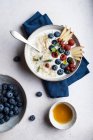 Top view bowl of delicious porridge topped with blueberries and raspberries near slices of pear served on table during breakfast — Stock Photo