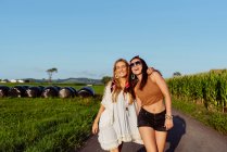 Due amiche felici vestite con abiti estivi che si divertono fuori da un furgone vintage in una giornata di sole — Foto stock