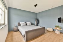 Комфортне ліжко з подушками, розташованими біля вікна в світлій спальні в сучасному будинку — стокове фото