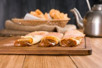 Frisch gerollte Crêpes gefüllt mit süßer Dulce de leche-Füllung, serviert auf einem Holzbrett auf einem Tisch mit Wasserkocher in der Küche — Stockfoto