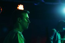 Serious young guys performing music on drums in club with neon green and blue lights — Stock Photo