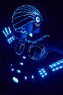 Personne sans visage en costume lumineux contemporain de cyborg de l'espace avec éclairage au néon et casque debout sur fond noir en studio sombre — Photo de stock
