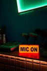 Micrófonos modernos en trípode colocados en la mesa en estudio oscuro con iluminación de neón antes de grabar podcast - foto de stock