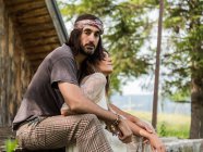 Attraktives Hippie-Paar, das sich auf der Veranda vor der Hütte umarmt — Stockfoto