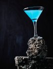 Blue Lagoon cocktail in crystal elegant glass placed on rough surface against black background — Stock Photo