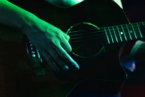 Chitarrista femminile irriconoscibile ritagliato che suona la chitarra acustica in un club leggero — Foto stock