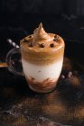 Von oben ein Glas süßen Dalgona-Kaffees mit schaumigem Belag auf dem Tisch mit Schokoladenwaffelrolle und Kakaopulver — Stockfoto
