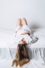 Do acima mencionado jovem fêmea grávida tocando barriga enquanto deitado na cama e sorrindo alegremente — Fotografia de Stock