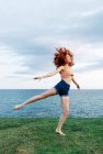 Full body of barefoot female dancing on coast of rippling sea — Stock Photo