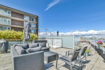 Veranda mit Sofa gegen Sessel und Topfpflanzen unter wolkenlosem blauen Himmel an sonnigen Tagen — Stockfoto
