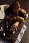 Vista dall'alto dei funghi Boletus edulis tagliati crudi su tagliere di legno con aglio e prezzemolo in cucina leggera durante il processo di cottura — Foto stock