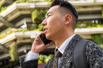 Jeune entrepreneur ethnique masculin avec cravate impatient tout en parlant sur téléphone portable en ville — Photo de stock