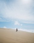 Corpo inteiro visão traseira da fêmea descalça no vestido passeando na duna arenosa no deserto — Fotografia de Stock
