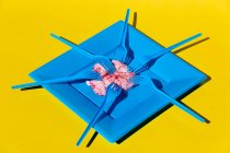 Haufen pinkfarbener roher Gehirne serviert auf blauem Teller mit Plastikgabel auf gelbem Hintergrund in hellem, modernem Kreativstudio — Stockfoto
