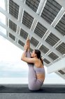 Ganzkörper-Seitenansicht der sportlichen Frau praktiziert Urdhva Mukha Paschimottanasana Haltung auf der Straße in der Nähe von modernen Solarzellen während Yoga-Sitzung — Stockfoto