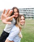 Fröhliche Freundinnen lächeln in die Kamera und amüsieren sich auf grünem Gras im Hof — Stockfoto
