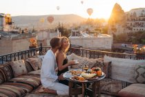 Vista lateral de amar a esposa beijando masculino enquanto come sobremesa e bebe chá juntos no terraço — Fotografia de Stock