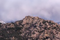 Piedras ásperas cubiertas de musgo y arbustos ubicados en la cima de la montaña nevada en el Parque Nacional Sierra de Guadarrama en Madrid, España - foto de stock