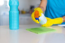 Ernte anonyme Frau in gelben Gummihandschuhen, die beim Putzen helle Küche mit Waschmittel besprüht — Stockfoto