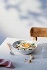 Високий кут керамічної чаші з турецькими яйцями розмістили на столі біля склянки води і виделки. — стокове фото