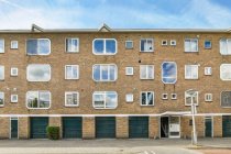 Zeitgenössisches Mehrfamilienhaus mit Ziegelwänden und Fenstern in verschiedenen Formen vor wolkenlosem blauen Himmel an der Stadtstraße — Stockfoto