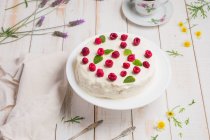 Von oben leckerer gesunder Keto-Crepe-Kuchen mit Erythrit-Süßstoff, dekoriert mit reifen Himbeeren, serviert auf Holztisch mit dekorativen Zweigen in der Küche — Stockfoto