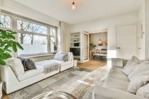 Interior da sala de estar contemporânea com tapete entre sofás com almofadas e xadrez em casa de luz — Fotografia de Stock