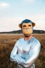 Pessoa anônima em máscara de macaco geométrico olhando para a câmera no campo amarelo no fundo embaçado — Fotografia de Stock