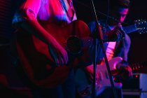 Mann spielt Gitarre, während Frau im Club mit Neonlicht singt und singt — Stockfoto