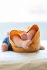 Anonymous cute barefooted baby lying alone on comfortable bed in sunny morning at home — Stock Photo