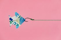Gancio on line tirando origami pesce a forma di banconota in euro come concetto di ricchezza e denaro guadagnando sullo sfondo rosa — Foto stock