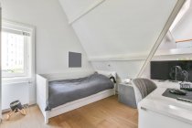 Interior of kid bedroom with comfortable bed and computer placed on working desk in attic of light house — Stock Photo