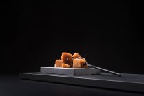 Gourmet marmelo pasta de geleia em placa de cerâmica sobre fundo preto com colher — Fotografia de Stock