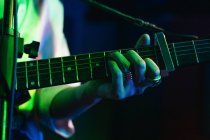 Zugeschnittene unkenntliche Gitarristin spielt Akustikgitarre in leichtem Club — Stockfoto