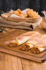 Свежевываренные блины, наполненные сладкой начинкой из теста, подаются на деревянной доске на столе с чайником на кухне — стоковое фото