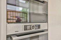 Design criativo de construído em microondas e painel de controle do forno refletindo flores florescentes em casa — Fotografia de Stock