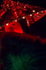 Rätselhafte Frau in kreativem traditionellem Outfit und vietnamesischer Kopfbedeckung mit roter Beleuchtung im dunklen Studio auf schwarzem Hintergrund während des Auftritts — Stockfoto