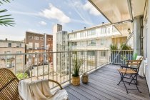 Amplia terraza de madera con cómodas sillas y plantas en maceta en la moderna casa de apartamentos - foto de stock