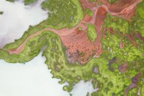 Vue par drone de formations brunes rocheuses rugueuses entourées de plantes vertes luxuriantes couvertes d'un épais brouillard dans la nature islandaise — Photo de stock