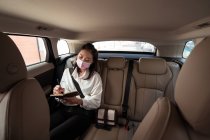 Frau in offizieller Kleidung in Schutzmaske schreibt in Notizblock, während sie auf dem Beifahrersitz im komfortablen Führerhaus sitzt — Stockfoto