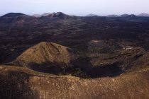 Vue paysage du vignoble dans le cratère du volcan contre les monts secs sous un ciel clair à Geria Lanzarote Îles Canaries Espagne — Photo de stock