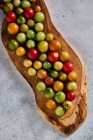 Dall'alto di pomodori ciliegia rossi maturi e acerbi raccolti in fattoria durante stagione di raccolto — Foto stock