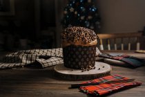 Panettone horneado casero dulce en soporte de madera redondo cerca del cuchillo para celebrar la Navidad - foto de stock
