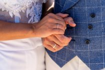 Ernte gesichtsloses Ehepaar in Hochzeits-Outfits Händchen haltend mit Trauringen bei Tageslicht — Stockfoto