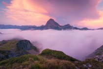 Nebbia bianca spessa che galleggia vicino a cresta rocciosa ruvida di montagna contro cielo nuvoloso nella natura selvaggia della Spagna durante sera estiva — Foto stock
